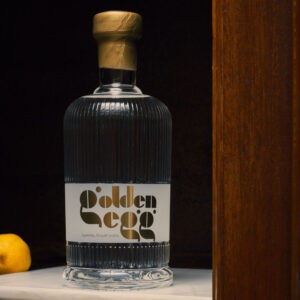 a bottle of golden egg vodka, on a bar back with a lemon in the background